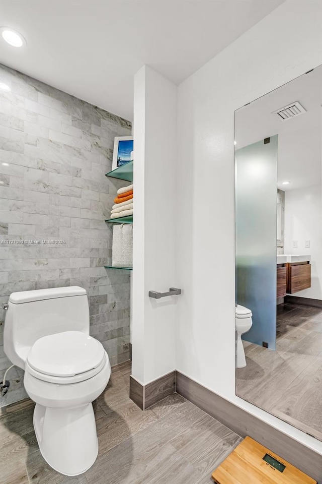 bathroom with toilet, vanity, and tile walls