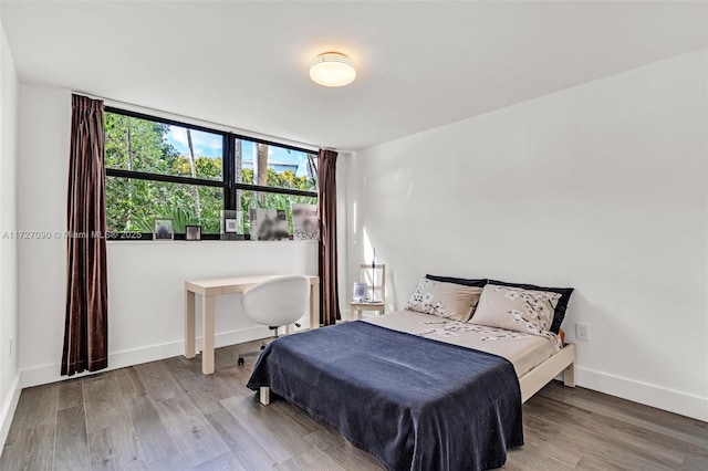 bedroom with floor to ceiling windows and hardwood / wood-style flooring