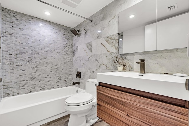 full bathroom with tiled shower / bath combo, vanity, tile walls, toilet, and hardwood / wood-style flooring