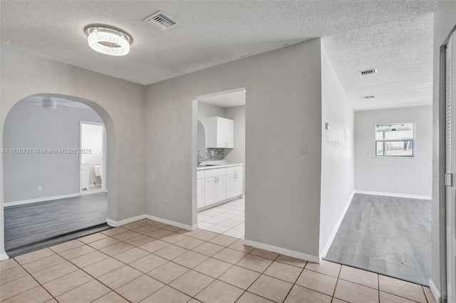 unfurnished room featuring sink, light tile patterned flooring, and a textured ceiling