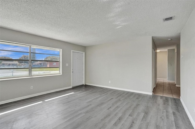 unfurnished room featuring light wood-type flooring and a textured ceiling