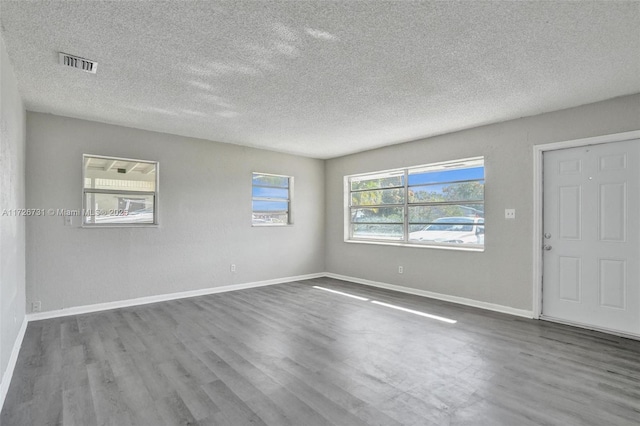 unfurnished room with hardwood / wood-style flooring and a textured ceiling