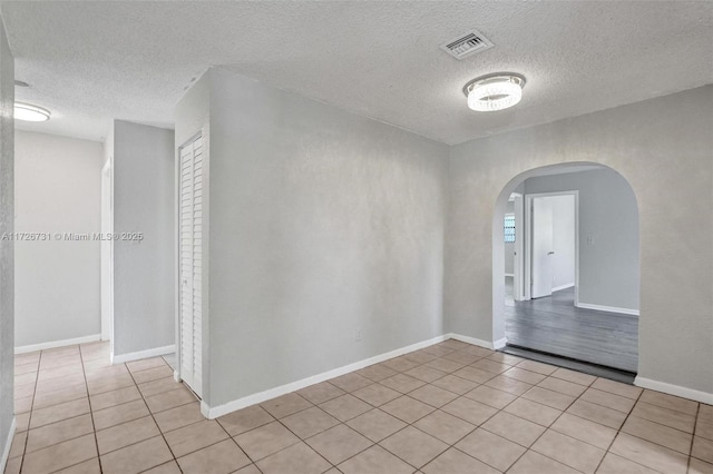 spare room featuring light tile patterned flooring and a textured ceiling