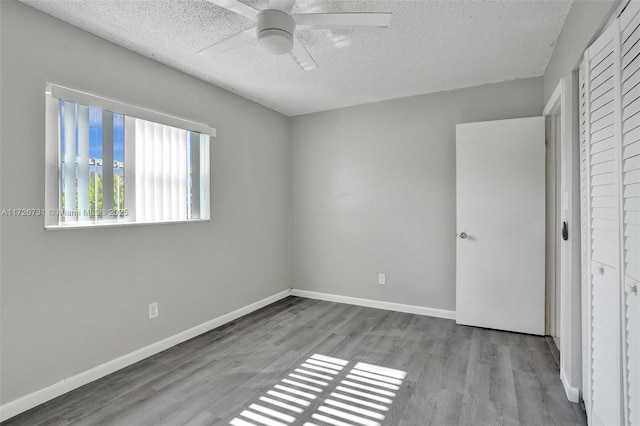 unfurnished bedroom with ceiling fan, a textured ceiling, a closet, and light wood-type flooring