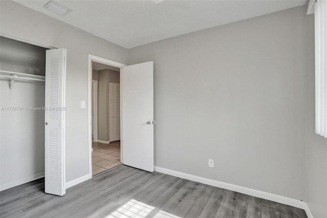 unfurnished bedroom with light wood-type flooring and a closet