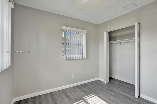 unfurnished bedroom featuring a closet, a textured ceiling, and wood-type flooring