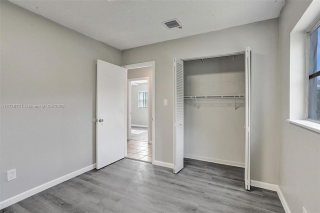 unfurnished bedroom featuring light wood-type flooring, a closet, and a textured ceiling