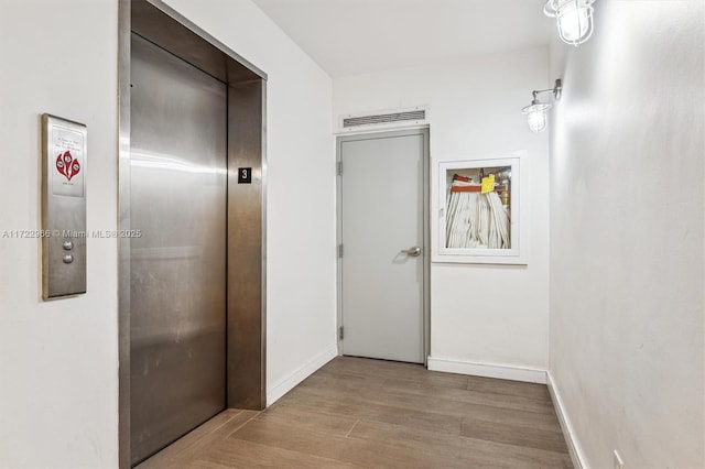 hall with elevator and light wood-type flooring