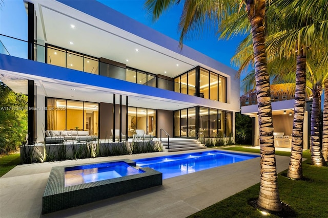 rear view of house with a swimming pool with hot tub and a patio