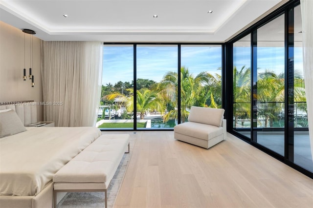 bedroom featuring light hardwood / wood-style flooring, access to exterior, floor to ceiling windows, and multiple windows