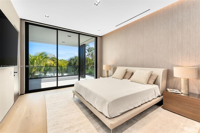 bedroom with expansive windows, access to outside, and light hardwood / wood-style flooring