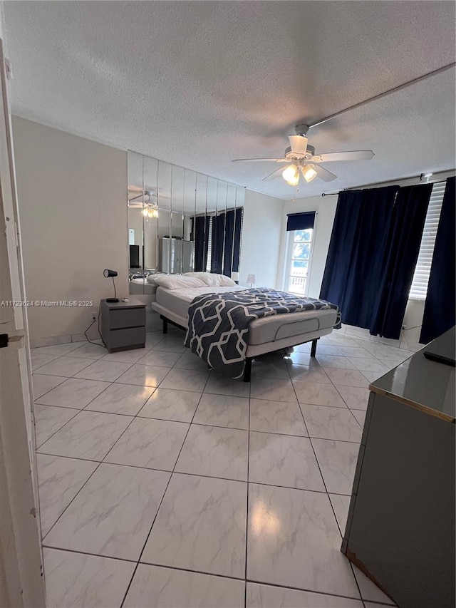 bedroom with ceiling fan and a textured ceiling