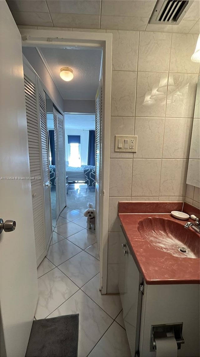 bathroom with tile patterned flooring, tile walls, and sink