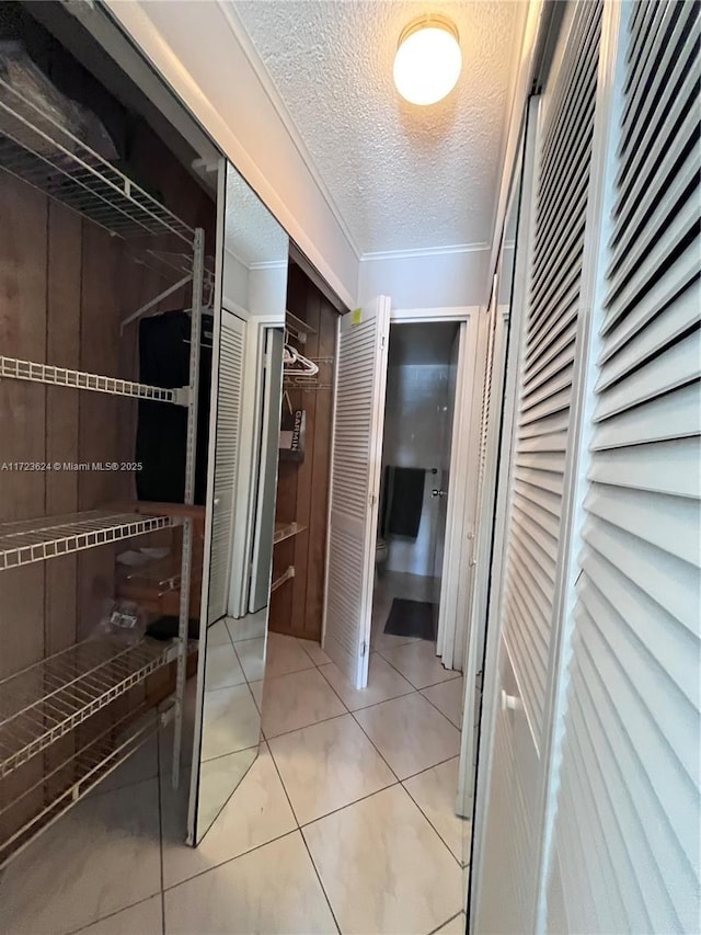 hall with light tile patterned flooring and a textured ceiling