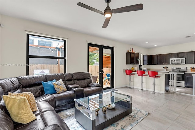 tiled living room featuring ceiling fan and french doors