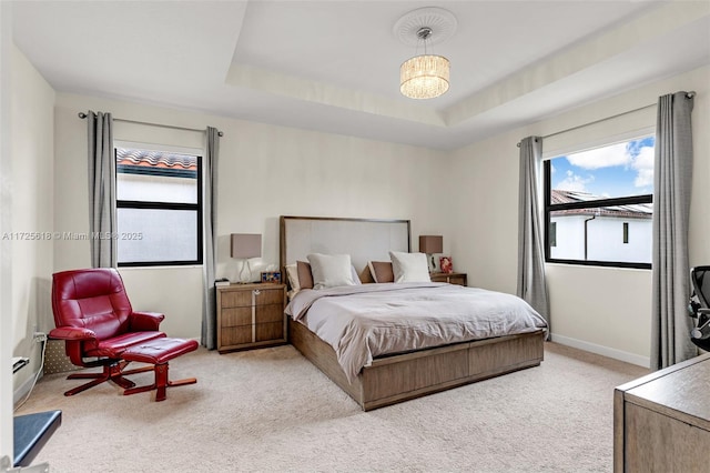 bedroom with a raised ceiling and light colored carpet