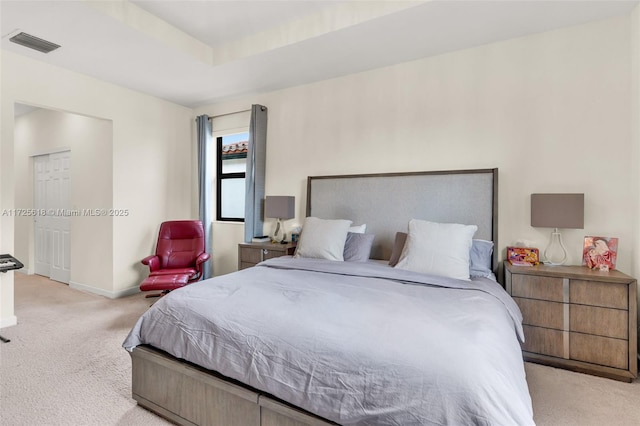 bedroom featuring light colored carpet and a tray ceiling