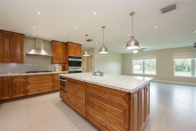 kitchen featuring wall chimney exhaust hood, a kitchen island, stainless steel appliances, decorative backsplash, and hanging light fixtures