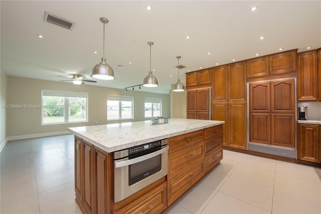 kitchen with light tile patterned flooring, brown cabinetry, stainless steel oven, and visible vents