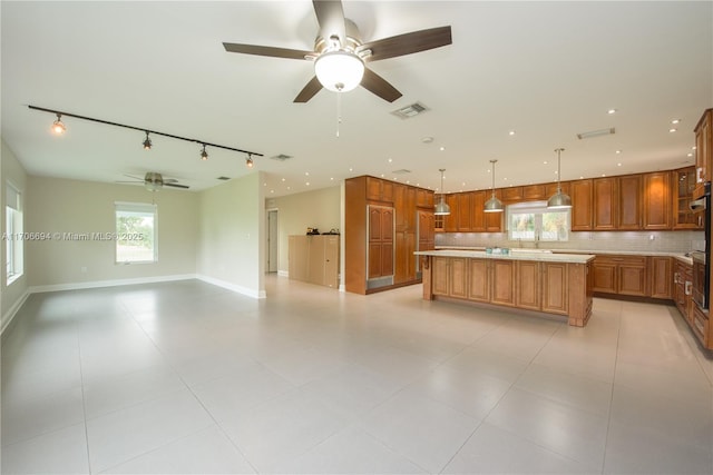 kitchen with light countertops, backsplash, visible vents, and brown cabinets