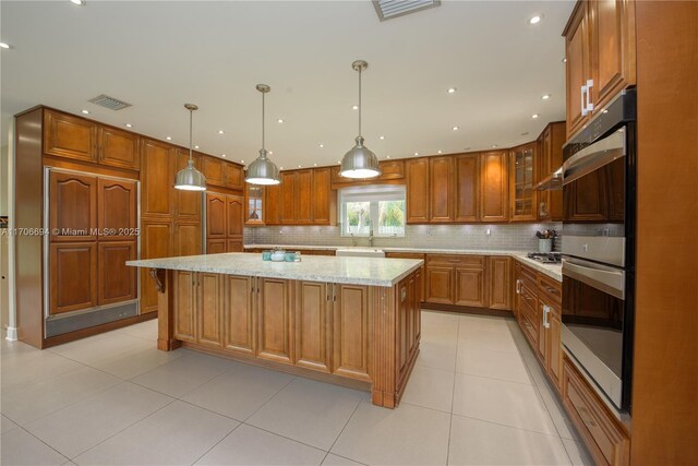 kitchen featuring decorative light fixtures, light tile patterned floors, black stovetop, stainless steel double oven, and wall chimney exhaust hood