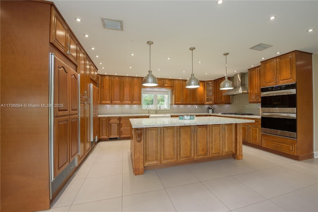 kitchen featuring wall chimney range hood, visible vents, stainless steel double oven, and gas cooktop