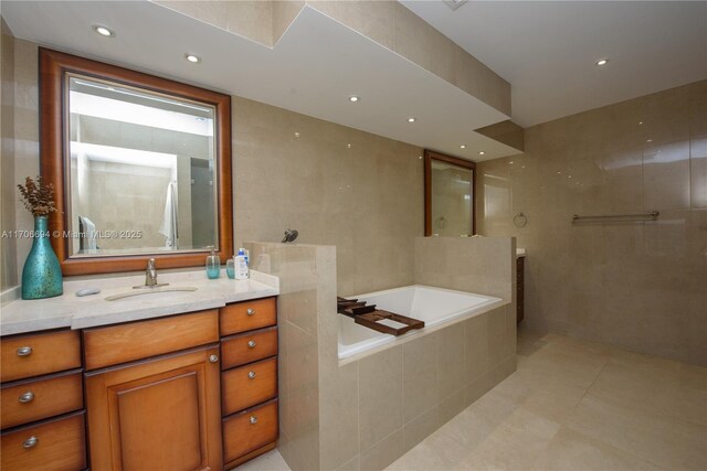 bathroom featuring tiled bath, tile walls, vanity, and tile patterned flooring