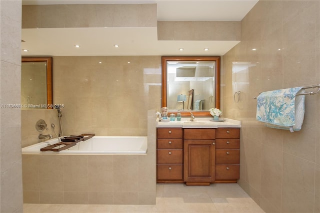 bathroom featuring a garden tub, vanity, tile walls, and tile patterned floors