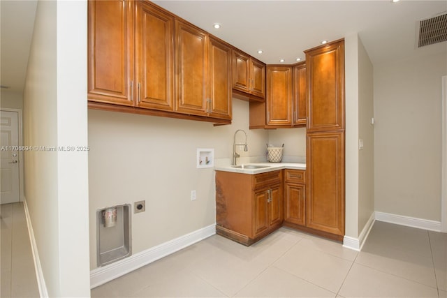 kitchen featuring light tile patterned floors, a sink, visible vents, light countertops, and brown cabinetry