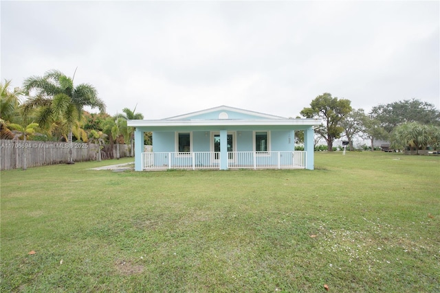 view of front of house featuring stucco siding, fence, covered porch, and a front yard