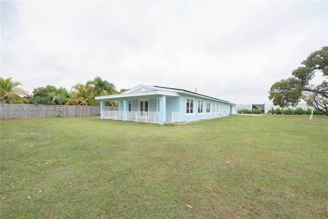 view of side of property featuring covered porch and a yard