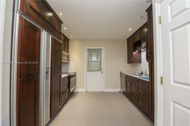 kitchen with backsplash, sink, light tile patterned floors, hanging light fixtures, and dishwashing machine