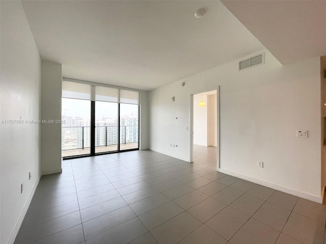 tiled empty room featuring expansive windows