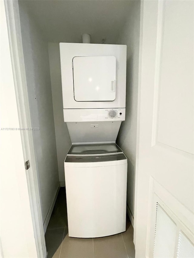 washroom featuring stacked washer and dryer and light tile patterned flooring