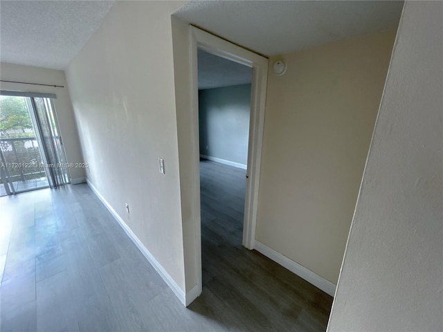 empty room with a textured ceiling, baseboards, and wood finished floors