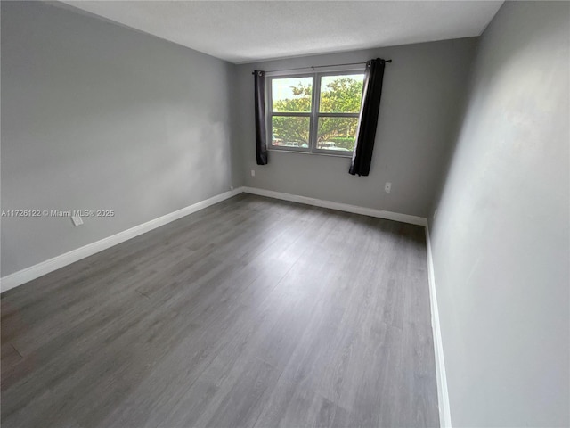 spare room with dark wood-type flooring and baseboards