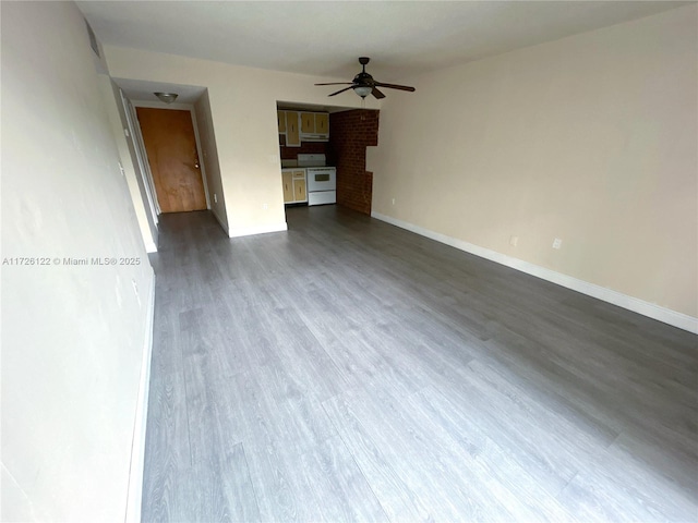 unfurnished living room with ceiling fan, baseboards, and wood finished floors