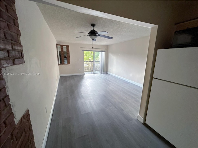 interior space featuring ceiling fan, a textured ceiling, baseboards, and wood finished floors