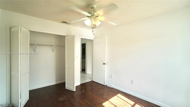 unfurnished bedroom featuring ceiling fan, a closet, dark hardwood / wood-style floors, and a textured ceiling