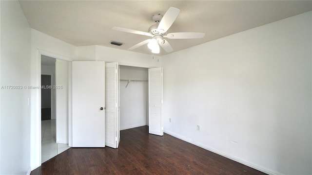 unfurnished bedroom with ceiling fan, dark wood-type flooring, and a closet