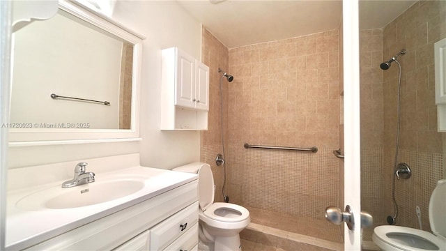 bathroom featuring toilet, vanity, and tiled shower