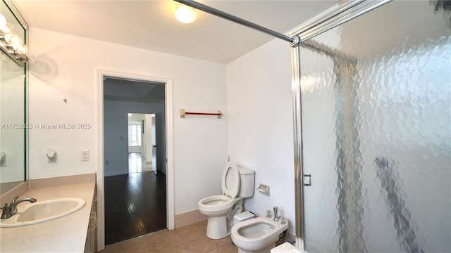 bathroom with tile patterned flooring, vanity, toilet, walk in shower, and a bidet
