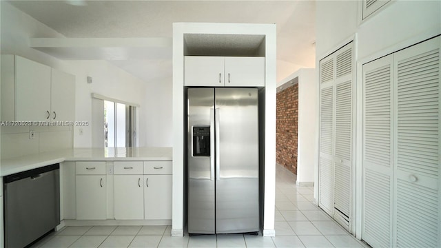 kitchen with kitchen peninsula, white cabinetry, light tile patterned floors, and stainless steel appliances