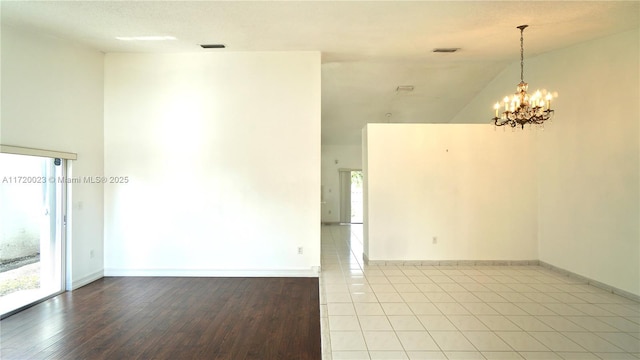 spare room with an inviting chandelier, light tile patterned floors, and lofted ceiling
