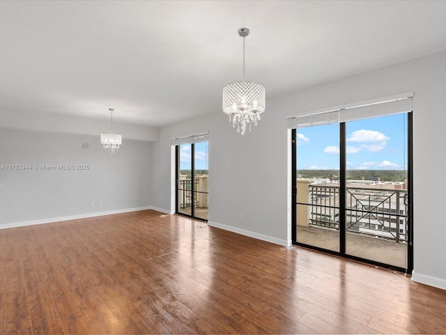 empty room featuring an inviting chandelier and hardwood / wood-style flooring