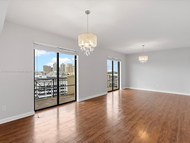 spare room featuring hardwood / wood-style floors and a chandelier