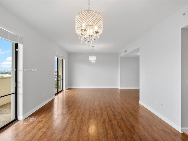 empty room featuring wood-type flooring and a notable chandelier