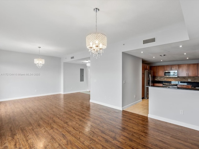 unfurnished living room featuring light hardwood / wood-style floors, electric panel, and a notable chandelier