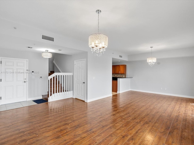 unfurnished living room with hardwood / wood-style floors and a chandelier