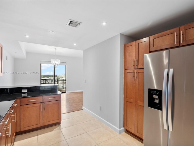 kitchen featuring stainless steel refrigerator with ice dispenser, an inviting chandelier, light tile patterned floors, and decorative light fixtures